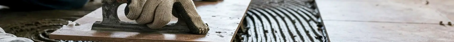 Carreleur réalisant la pose d'un carrelage couvert par une assurance décennale