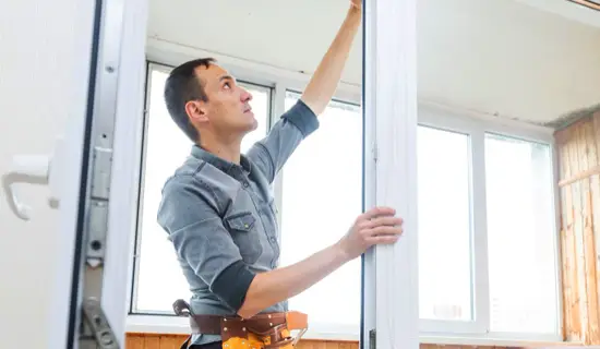 Artisan menuisier installant une fenêtre couvert par une assurance décennale